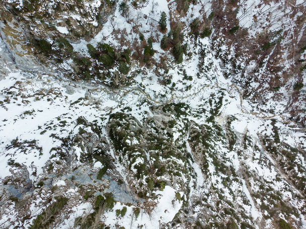 Drop down view of a mountain river flowing through winter forest. - 写真・画像