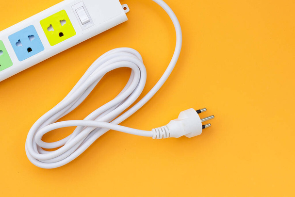 Electrical power strip and plug on yelow background. Top view - Photo, Image