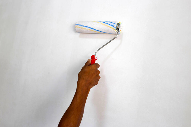 Rodillo de pintura de mano de trabajador, Pintura de una pared - Foto, imagen
