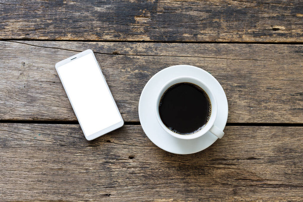closeup smartphone with coffee cup on wooden table top view,with clipping path - Valokuva, kuva