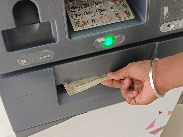 ATM Cash opname - Indiase roepies in ATM. Man neemt het geld op via geldautomaat, bedrijf Automatische verkoper Machine concept. - Foto, afbeelding