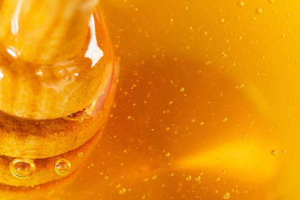 Olla de miel de madera con miel dorada y burbujas de aire. Extremo primer plano, macro - Foto, imagen