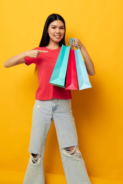 Retrato asiático hermosa mujer joven bolsas de compras en camiseta roja aislado fondo inalterado - Foto, Imagen