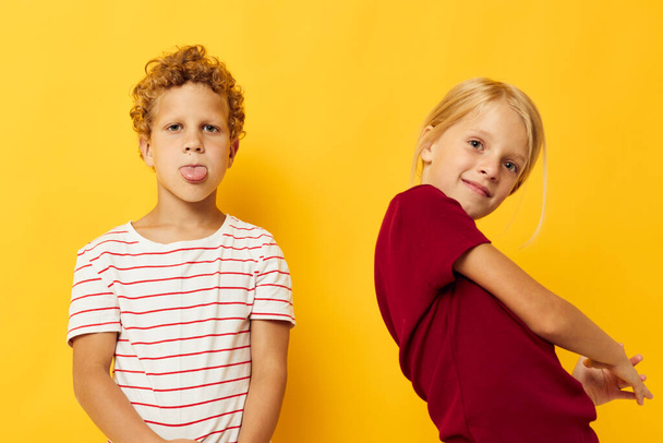 cheerful children standing side by side posing childhood emotions yellow background - Foto, afbeelding