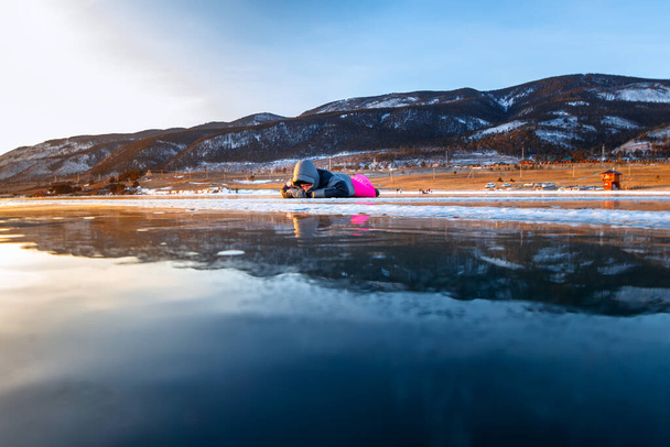 Girl laiing on cracked ice of a frozen lake Baikal - Foto, Imagen