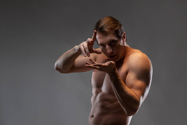 A young muscular man in an expressive pose. Beautiful muscles. - Foto, imagen