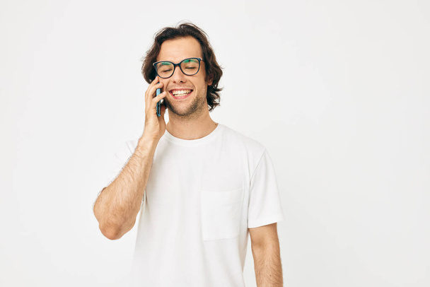 Cheerful man in a white T-shirt communication by phone isolated background - Valokuva, kuva