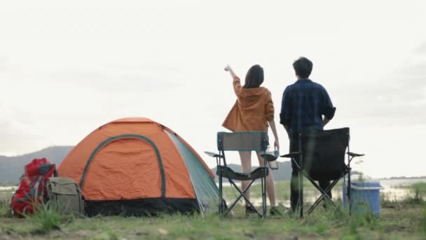 Jóvenes campistas de parejas asiáticas trekking en el parque de montañas celebrando el campamento de escalada exitosa en un paisaje hermoso y soleado fondo natural disfrutando de viajes de vacaciones. - Metraje, vídeo