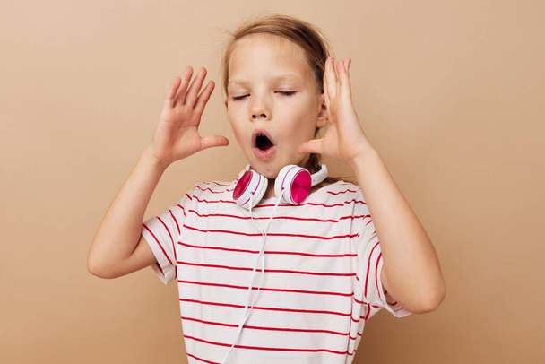 söpö tyttö raidallinen t-paita kuulokkeet ele kädet eristetty tausta - Valokuva, kuva