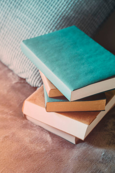 Stapel Bücher auf dem Bett im Zimmer, mit Papier ausgekleidet, neben dem Kissen. Mittlere Ebene. - Foto, Bild
