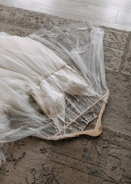 Bohemian style wedding dress with crystals embroidery, thrown on the floor. - Fotoğraf, Görsel