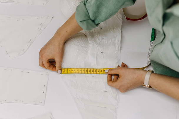 Модный дизайнер рабочего процесса, принимающий измерения шаблона для нового платья. Портной в своей студии.  - Фото, изображение