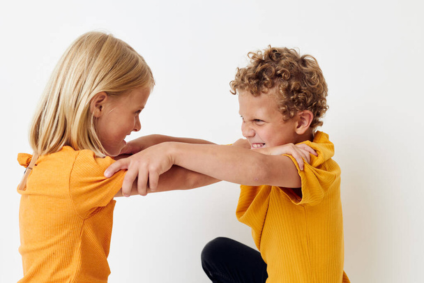 two joyful children in yellow t-shirts standing side by side childhood emotions light background unaltered - Foto, Imagen