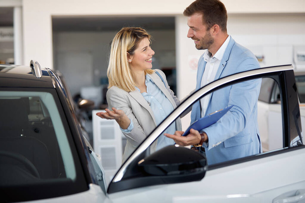 Girl buying a new car in city dealership and talking with salesm - Photo, image