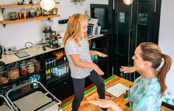 Mother dancing with her daughter while working in a coffee shop - Foto, imagen