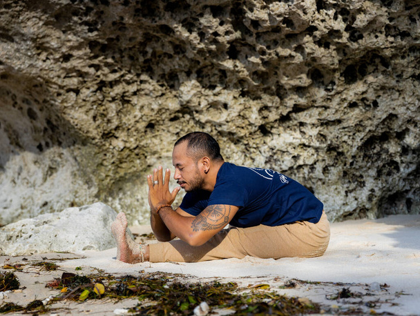 Yoga de plage. Homme asiatique pratiquant Paschimottanasana, assis vers l'avant Bend Pose. Mains dans le mudra namaste. Corps flexible. Exercice d'étirement. Une colonne vertébrale saine. Retraite de yoga à Bali. Plage de Thomas, Indonésie - Photo, image