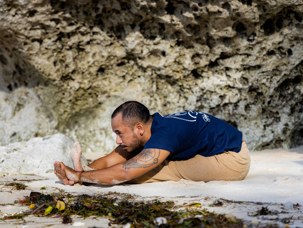 Yoga de plage. Homme asiatique pratiquant Paschimottanasana, assis vers l'avant Bend Pose. Corps flexible. Exercice d'étirement. Une colonne vertébrale saine. Concept d'autosoin. Retraite de yoga à Bali. Plage de Thomas, Indonésie - Photo, image