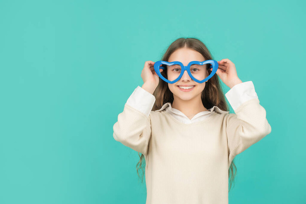 cheerful kid in party glasses on blue background with copy space, childhood - Foto, Imagem