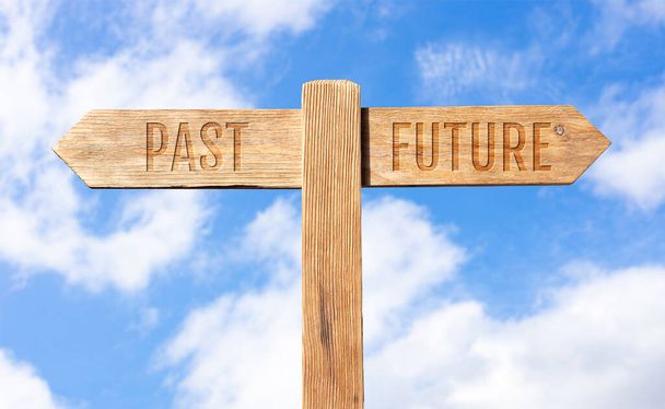 Прошлое или будущее. Деревянный указатель с сообщением на фоне неба - Фото, изображение