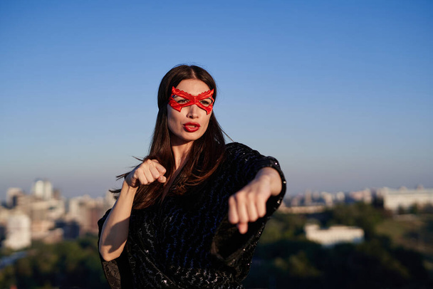 Ragazza supereroe in maschera fare pugilato utilizzando le mani sulla vista urbana - Foto, immagini