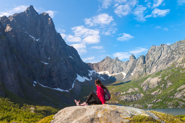Young tourist woman is sitting  on stone near mountain lake - Valokuva, kuva
