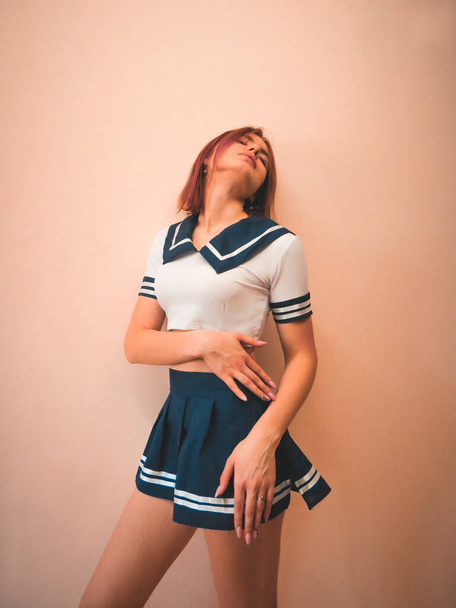 A young red-haired woman with a slender figure in the outfit of a university rugby team cheerleader, the concept of team sports games, competitions, girls cheerleaders - Valokuva, kuva