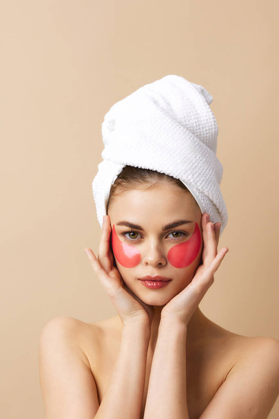 Nainen pyyhe päässään elehtii käsillään ihonhoito beige tausta - Valokuva, kuva