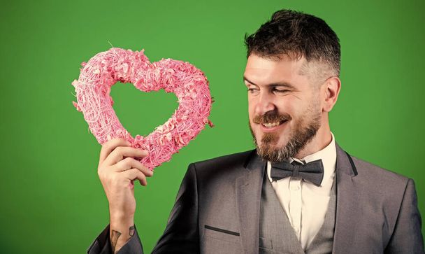 Hipster hold heart symbol love. Man formal suit celebrate valentines day green background. Spread love. Happy in love. Romantic macho flirting. Macho looking for girlfriend. Happy valentines day - Photo, Image