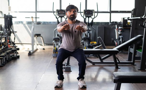 Young Indian athelete faire squats excerise à la salle de gym - concept de mode de vie sain, fitness et musculation. - Photo, image