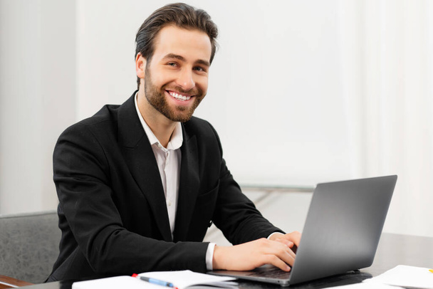 Happy smiling business man working from office. Successful male sitting at the desk, using laptop, develop a project - Foto, Imagem