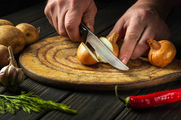プロのシェフは、昼食のためのスープを作るためにまな板にナイフでタマネギをカットします。野菜食の考え方. - 写真・画像
