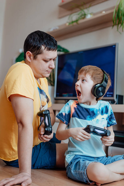 Family leisure father and son play video games, child redhead boy screaming lose. - Photo, Image