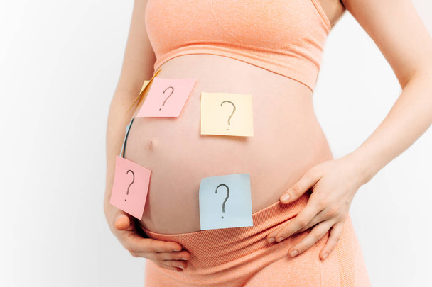 pregnant woman holding a paper with a question mark wondering about the gender of the baby. Expectant mother thinks about a newborn baby. Motherhood and upbringing. Planned pregnancy and IVF. - Φωτογραφία, εικόνα