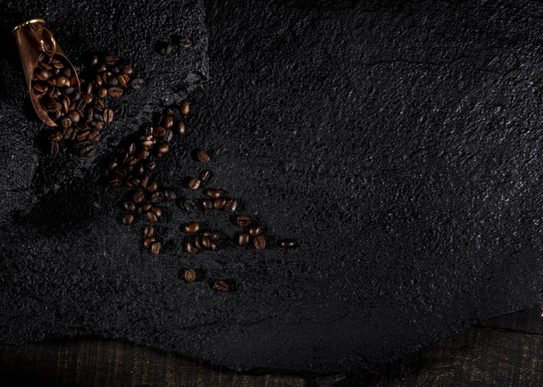 кавові зерна, розлиті на чорному камені
. - Фото, зображення