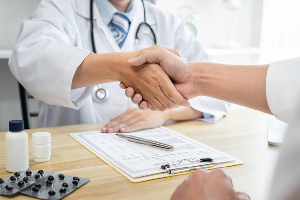 Male doctor in white coat shaking hands with the patient after successful treatment and recommend method recuperate. - Photo, image