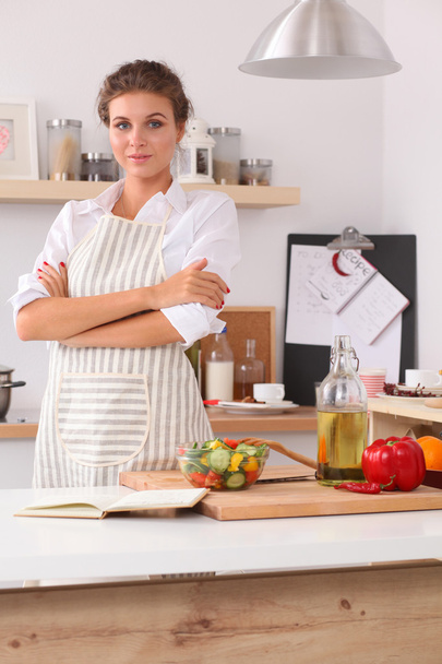Smiling young woman in the kitchen, isolated on christmas background - Foto, Imagen