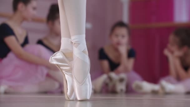 Entrenamiento de ballet: bailarinas con hermosos vestidos sentadas en el suelo y una de ellas bailando en primer plano - Imágenes, Vídeo