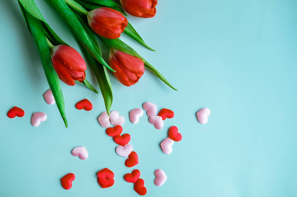 bouquet of red tulips with small hearts on a blue background, top view - Фото, зображення