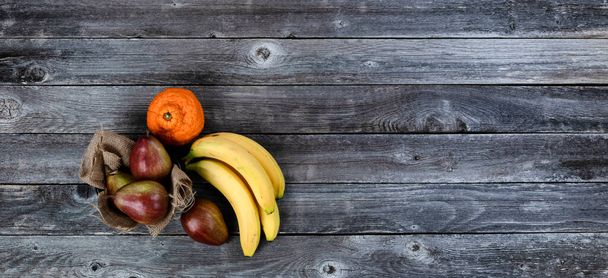 Vue de dessus de fruits mûrs composés de poires, bananes et orange sur une vieille table en bois  - Photo, image