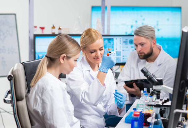 Professional team of scientists is working on a vaccine in a modern scientific research laboratory. Genetic engineer workplace. Future technology and science. - Photo, image