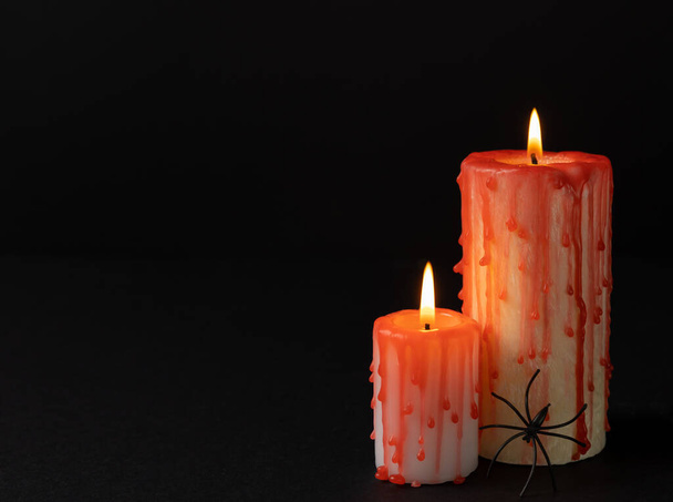 Composition from a group of scary bloody candles burning in the dark. Copy space on black paper background. Black magic ritual or scary Halloween rite.DIY Halloween decor. - 写真・画像