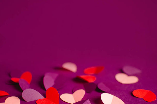 Close up pink purple red paper hearts on purple background. Happy Valentine Day. Greeting card. DIY Holiday and gift concept. Selective focus. Copy space - Photo, Image