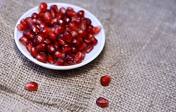 bright red pomegranate seeds on canvas background healthy food.  - 写真・画像