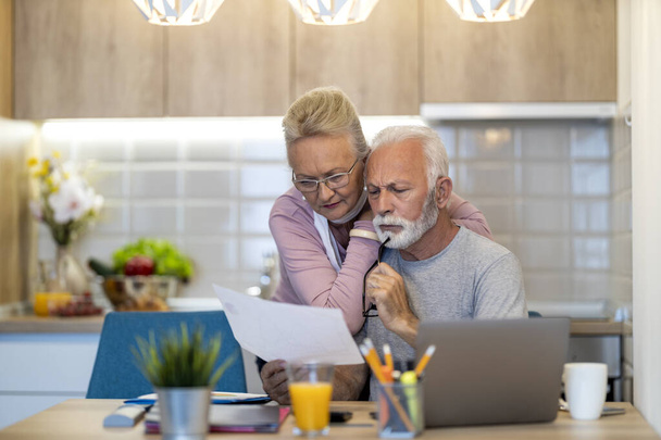 Ηλικιωμένο ζευγάρι που χρησιμοποιεί φορητό υπολογιστή στο σπίτι.Online shopping.People και τεχνολογία έννοια. - Φωτογραφία, εικόνα