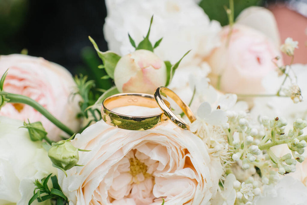 Zlaté snubní prsteny a krásná svatební kytice růží a eustomu v pozadí detailní záběr. Detaily a svatební tradice. - Fotografie, Obrázek