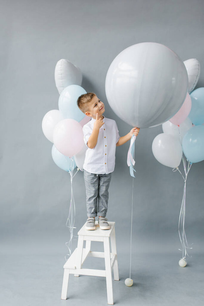 Πάρτι αποκάλυψης φύλου. Ένα τετράχρονο παιδί κρατά ένα μπαλόνι στα χέρια του για να ανακαλύψει το φύλο του αγέννητου παιδιού στην οικογένεια. Γενέθλια παιδιού - Φωτογραφία, εικόνα