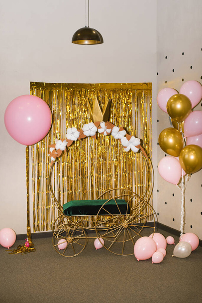 Photo zone for a girl's birthday party. Cinderella or princess carriage and pink gold balloons - Фото, изображение