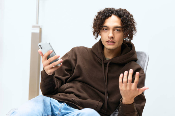 Молодой человек болтает в комнате по телефону технологии - Фото, изображение