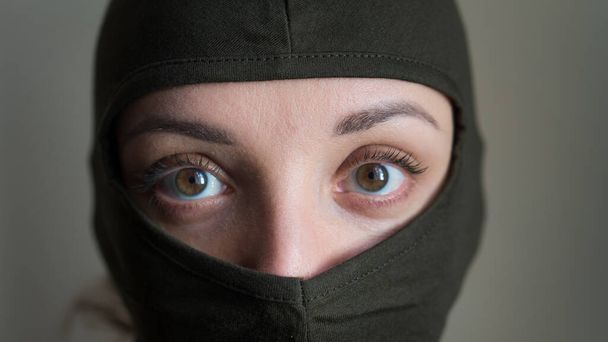 Frauenporträt eines jungen Mädchens mit khakifarbener Sturmhaube, nur Augen sind zu sehen, Wehrpflicht, Militär, Feminismus, Gleichberechtigungskonzept - Foto, Bild