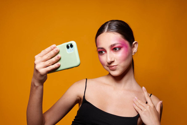 Beauty fashion female bright makeup posing black jersey with a phone in hand cropped view unaltered - Photo, image
